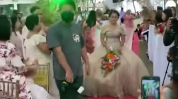 男人隐藏在新娘的婚纱中，帮助她走在强大的风中